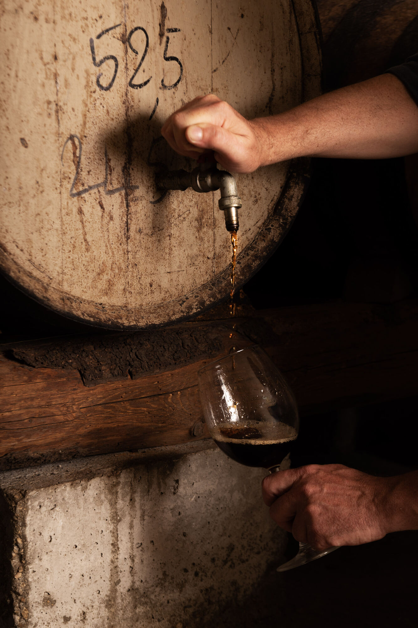Vino spillato dalla botte direttamente nel bicchiere in cantina